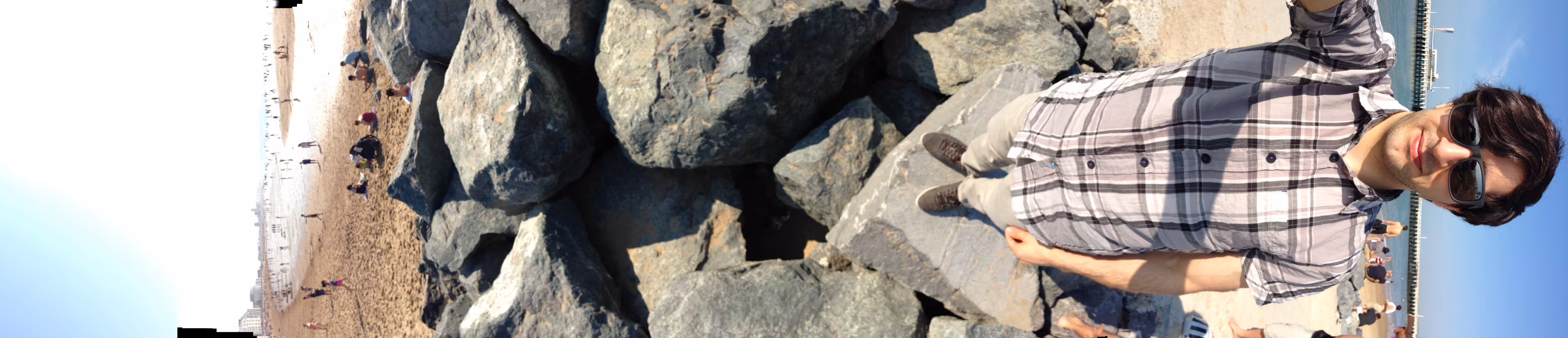 Vertical panorama turned sideways: from the sky over rocks by the water down to the photographer