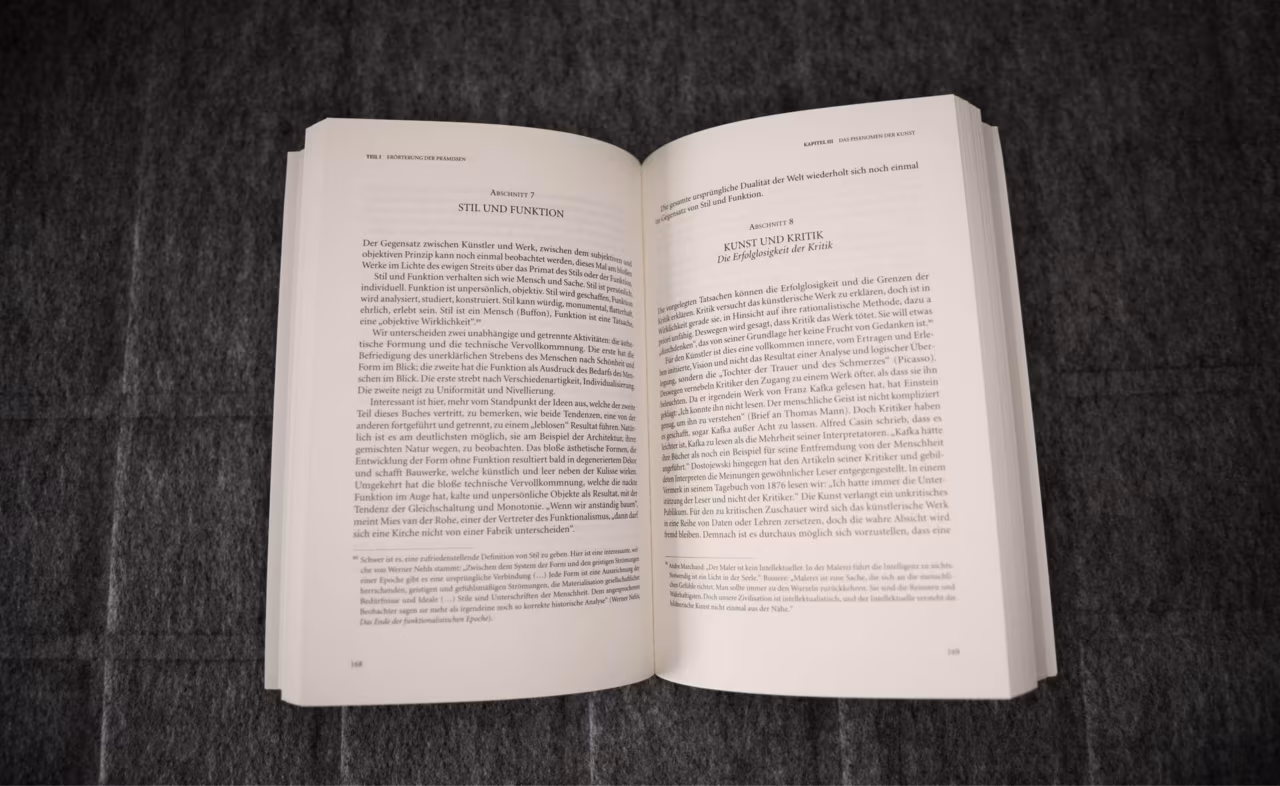 Open book on a grey blanket: a typeset spread with section headings, running heads and footnotes