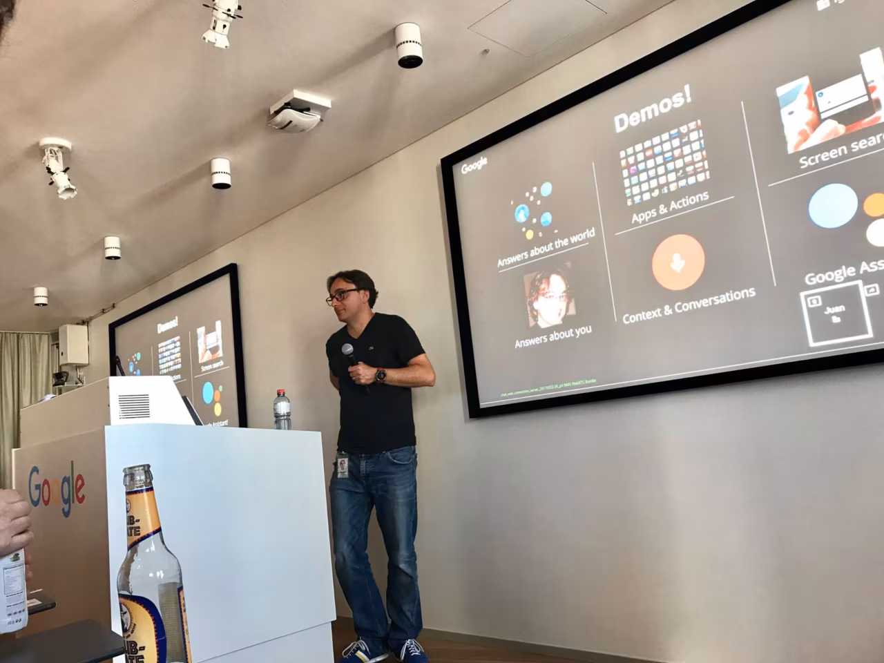 A speaker presenting Google Assistant demos on a large screen at Google Zurich