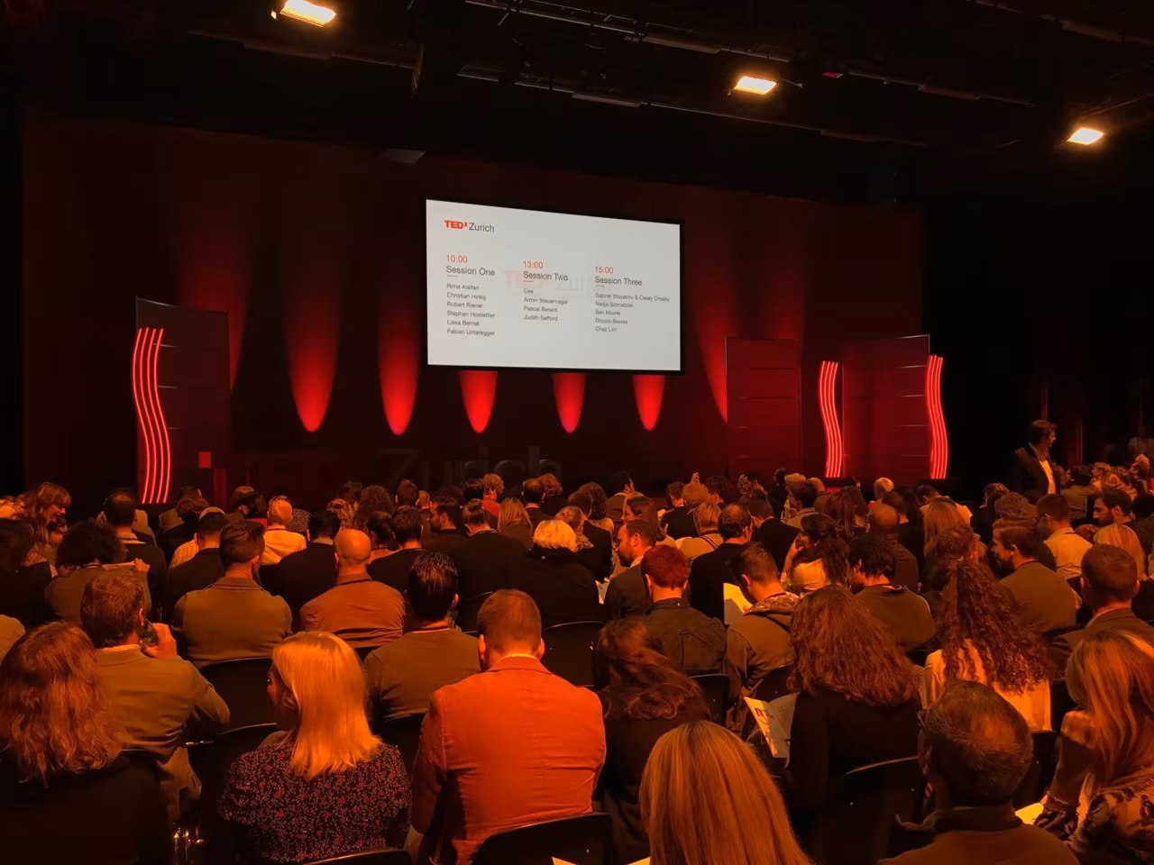 A full hall at TEDxZurich 2017, the session programme on the screen